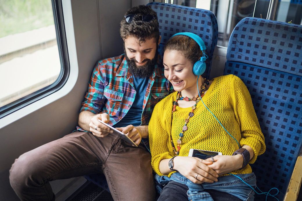 Auch bei der Zugfahrt wird Strom genutzt Glückliches Paar mit Tablet und Handy im Zug