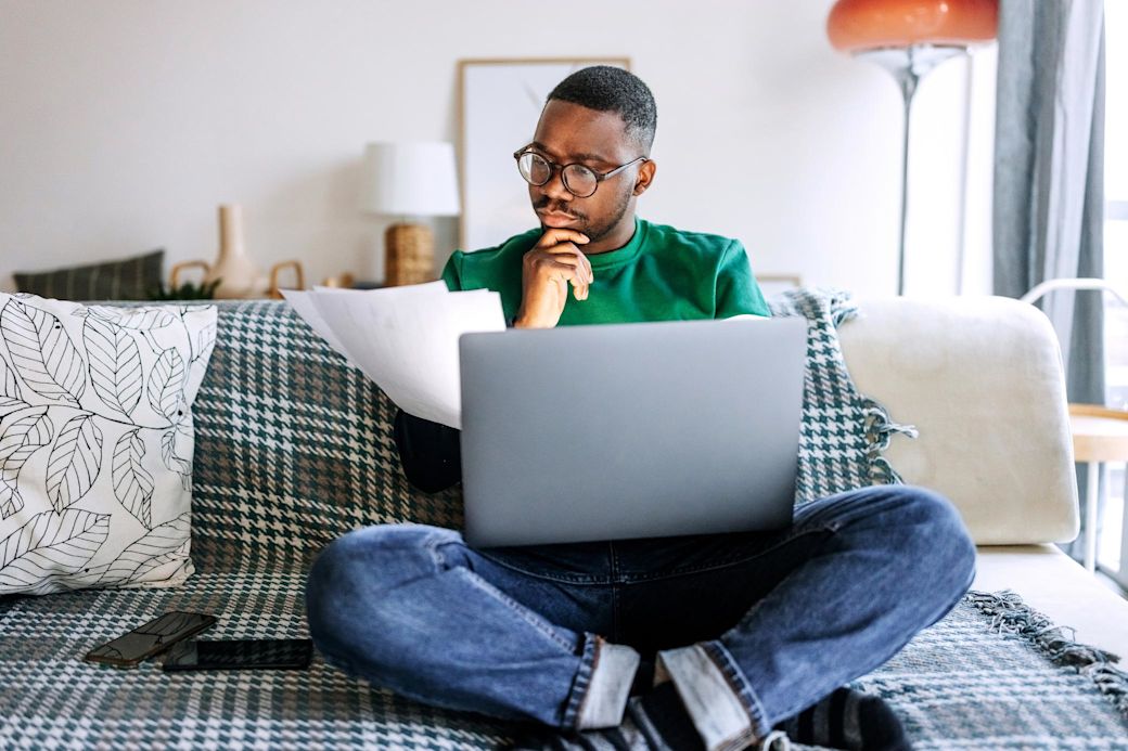 Energie wird digital und damit viel transparenter Junger Mann sitzt auf Sofa mit Laptop und überlegt