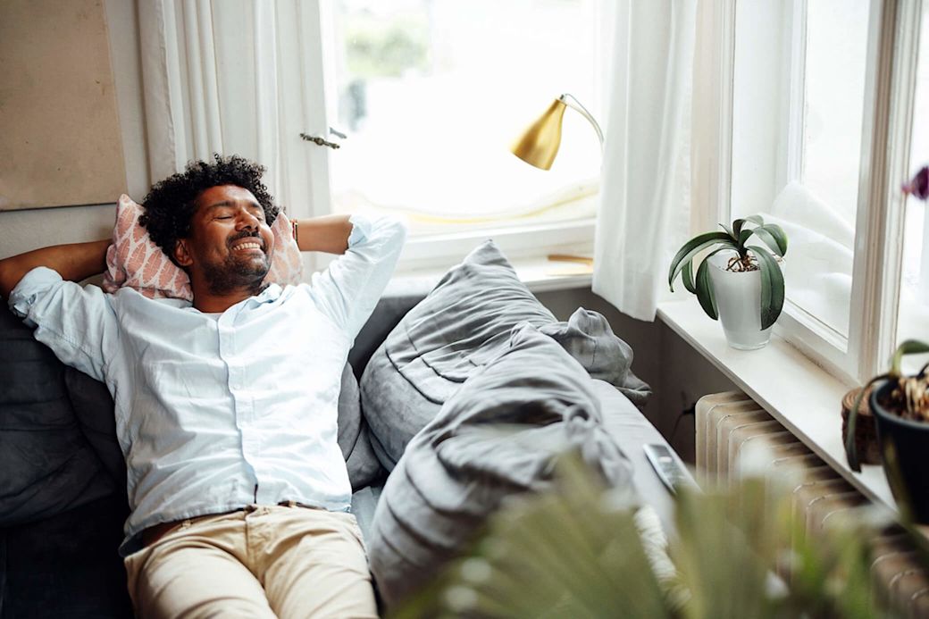 Entspannt dein zuhause genießen, dank smarter Energie  Ein Mann entspannt sich zuhause auf der Couch