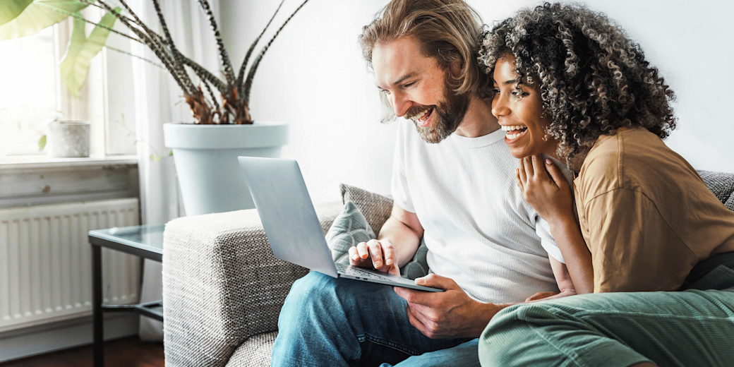 Glückliches Paar auf Sofa mit Laptop.