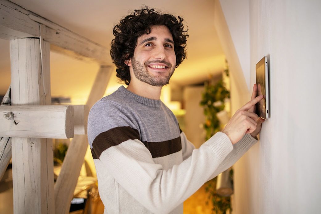 Ein HEMS optimiert den Energieverbrauch in deinem smarten Zuhause  Mann steuert sein HEMS zuhause über ein Tablet an der Wand