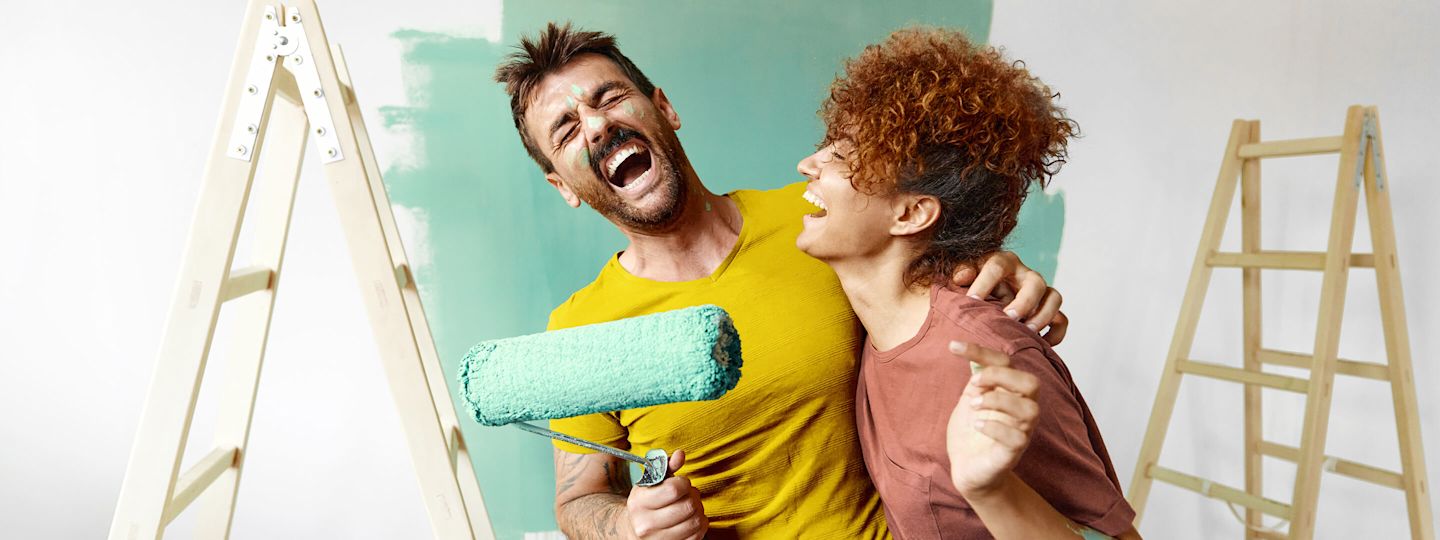 Was ist in Ökostrom drin? Grüne Energie für dein zuhause Junges, lachendes Paar streicht die Wohnung grün