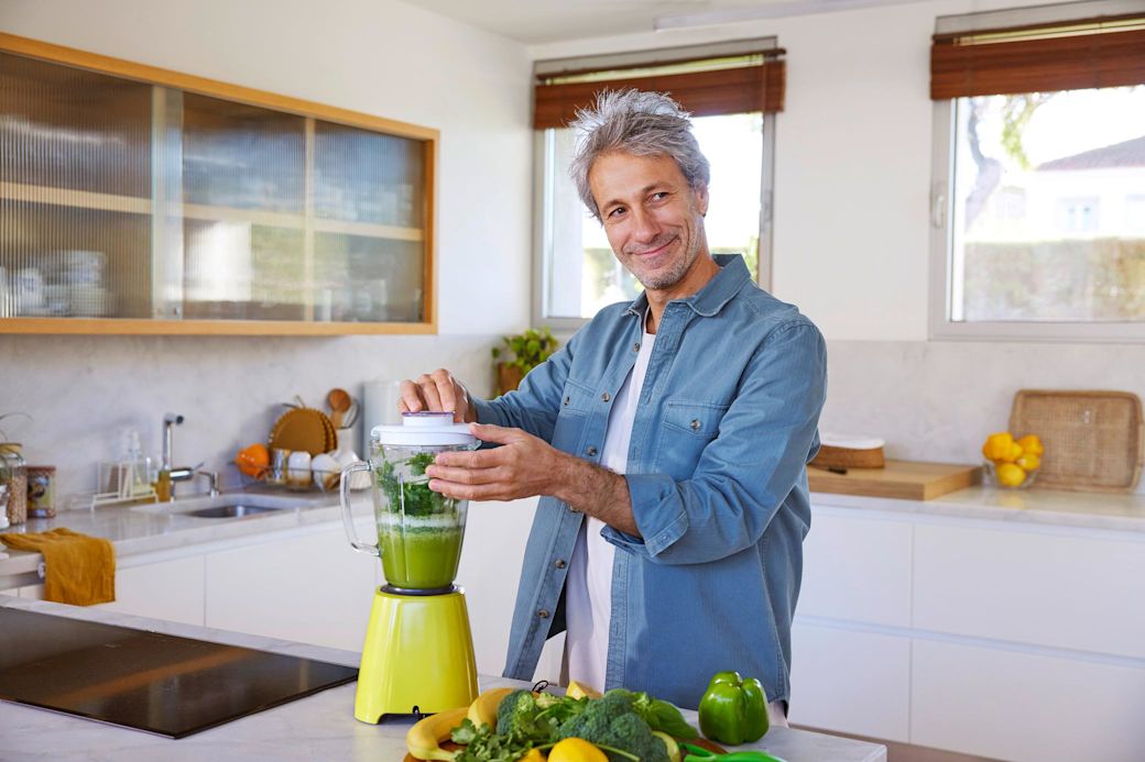 Grün gemischt: So ist auch Strom aus der Steckdose Mann bereitet grünen Smoothie in der Küche zu
