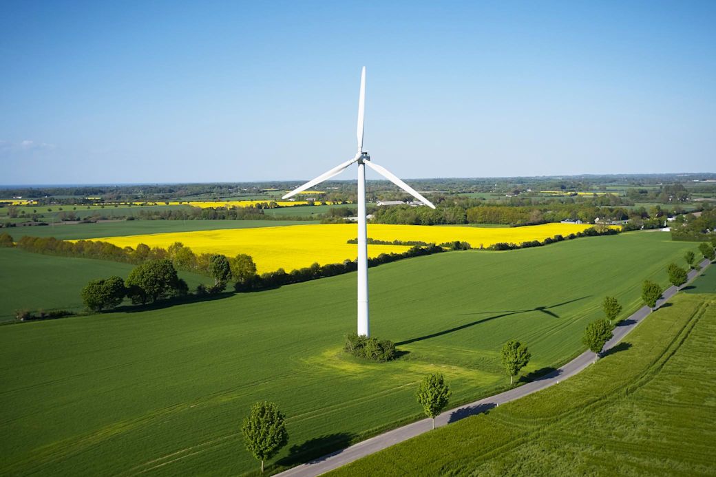 Erneuerbare Energien punkten mit niedrigen Strompreisen Ein Windrad mit Wiesen und einem Rapsfeld im Hintergrund