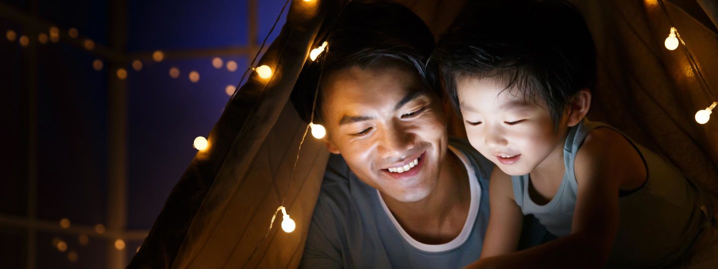 Vater und Sohn lesen abends bei wenig Licht ein Buch