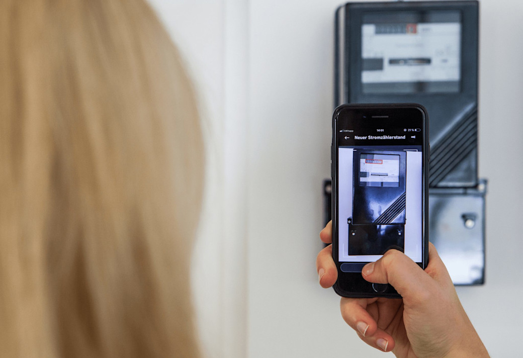 Frau erfasst neuen Stromzählerstand mit einer App auf einem Smartphone.