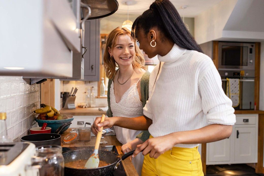 In der Küche ist der Stromverbrauch besonders hoch Zwei Freundinnen kochen eine Mahlzeit in der Küche