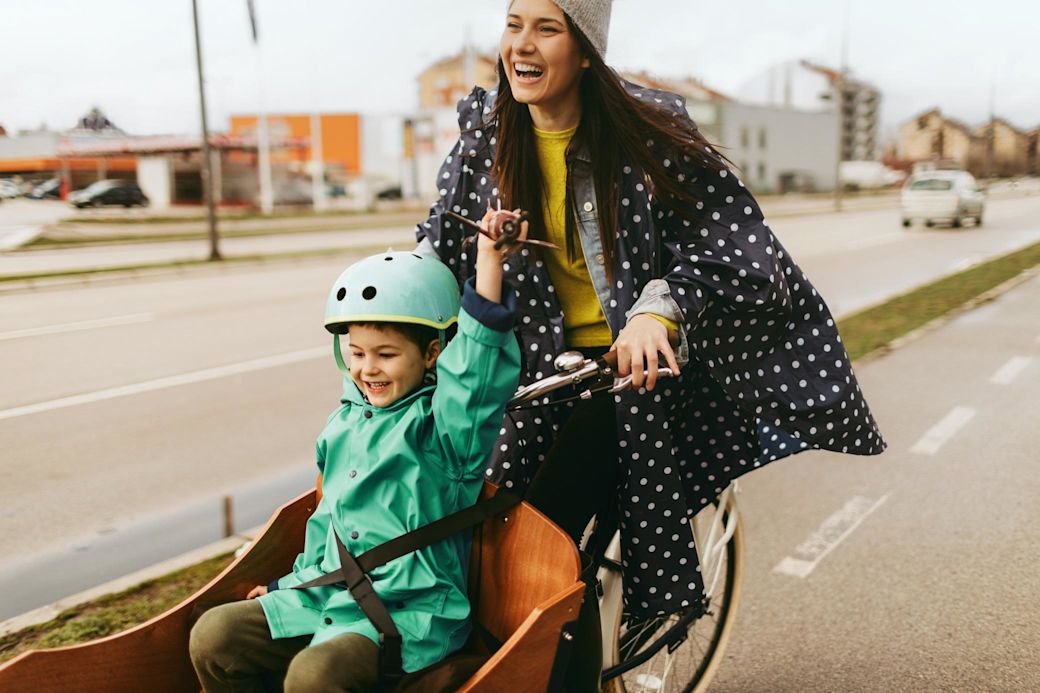 Mit dem Fahrrad fährst du nachhaltiger und gesünder Fröhliche Frau mit Lastenfahrrad und Kind in der Stadt