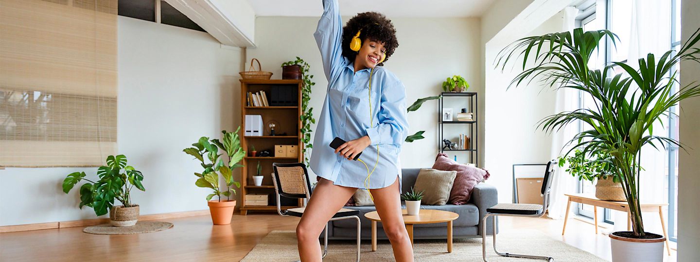 Energieeffizient und smart leben. Mit einem Smart Meter. Frau tanzt mit Kopfhörern in ihrem Wohnzimmer