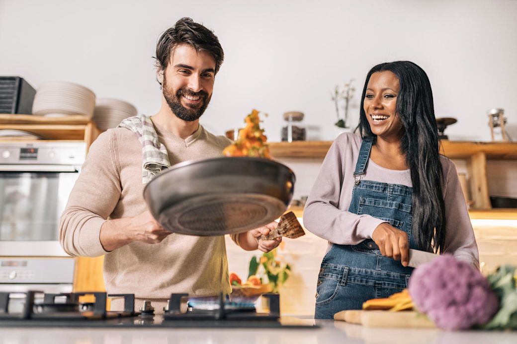 Junges Paar in der Küche beim Kochen mit Gasherd