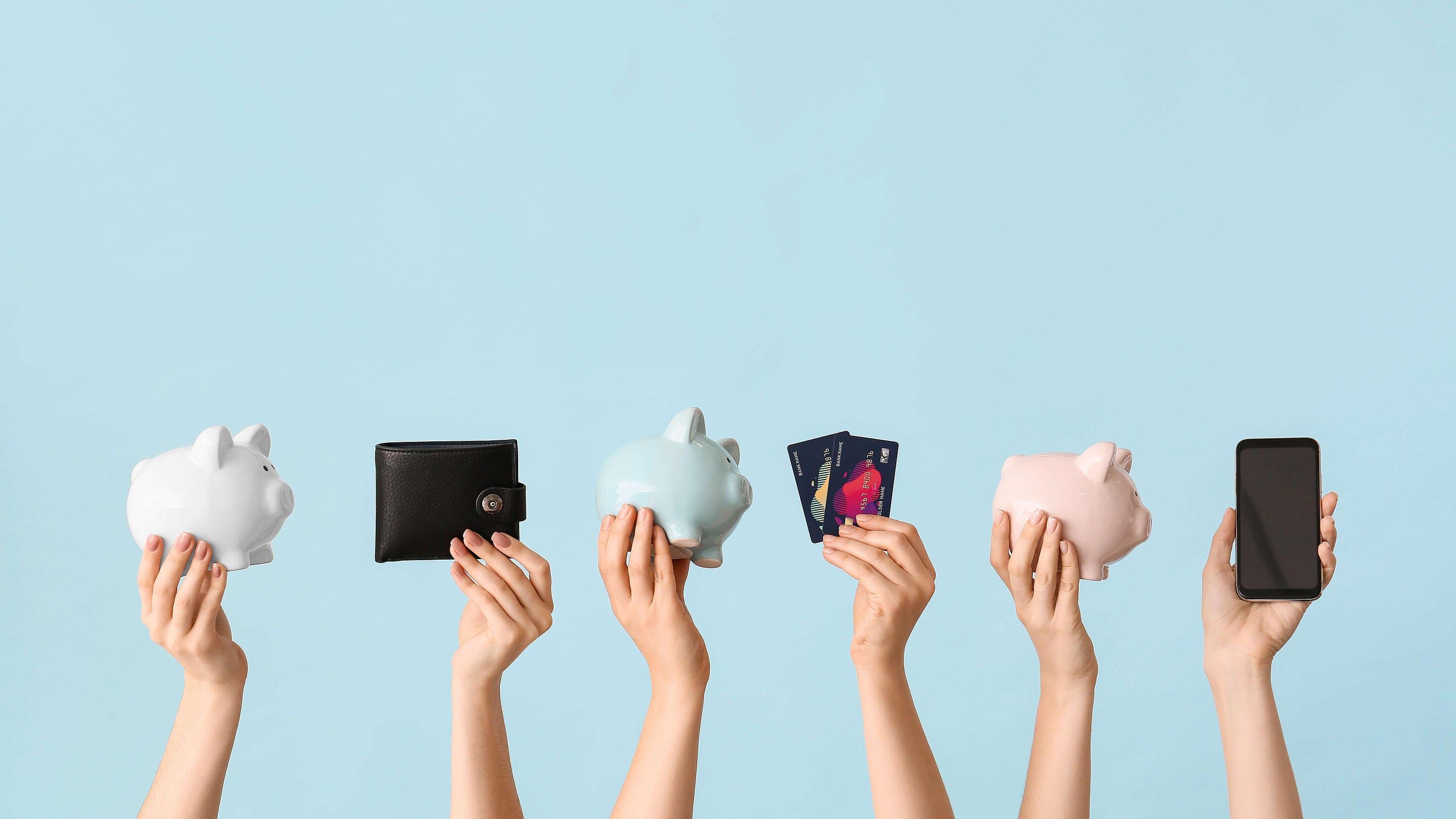 hands holding piggy banks, wallet, credit card, and phone