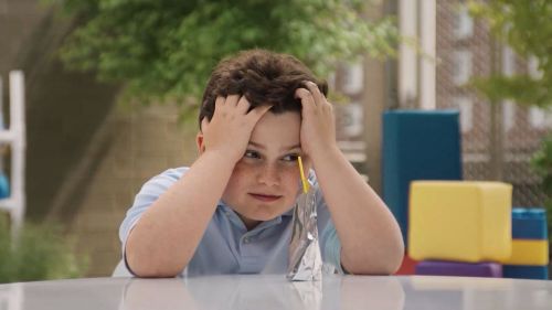 Kid looking frustrated with hands on head; Capri Sun pouch filled with water on table
