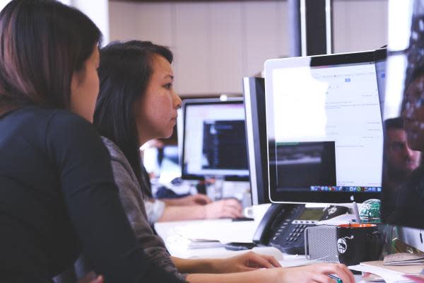 two people are sitting on a chair in front of their laptops