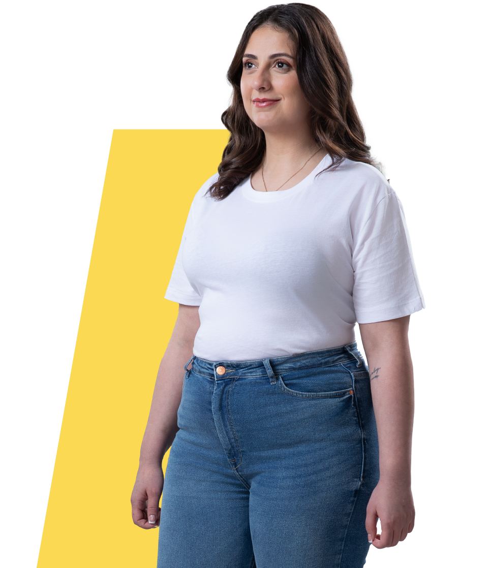 Uma mulher com excesso de peso/obesidade, em pé, à frente de um fundo colorido.