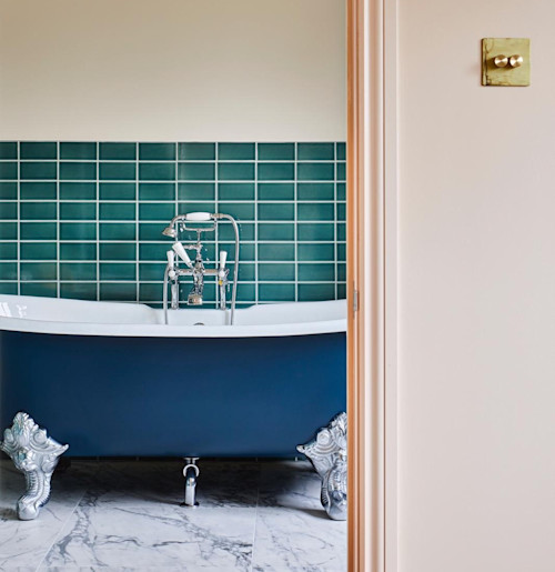 Roll top cast iron bath painted blue, framed by Setting Plaster walls by Farrow & Ball. A London loft conversion ensuite, interior design by Andrew Jonathan Design based in Crouch End.