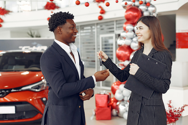Person handing over keys to a new car after driver got car insurance coverage before purchasing their vehicle