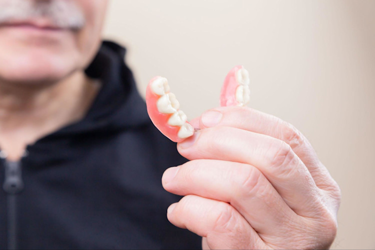 A person with dentures that is covered by their broader Medicare plan.