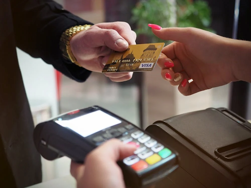 A person handing a credit card to the cashier to pay for items.