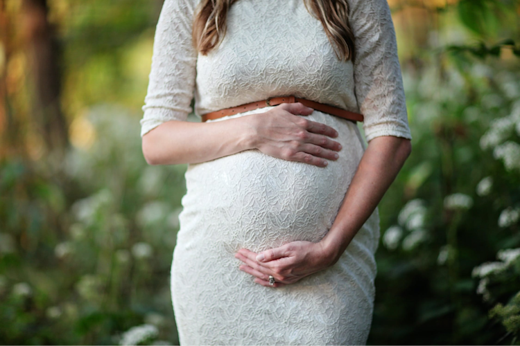 A woman that is pregnant holding her stomach.