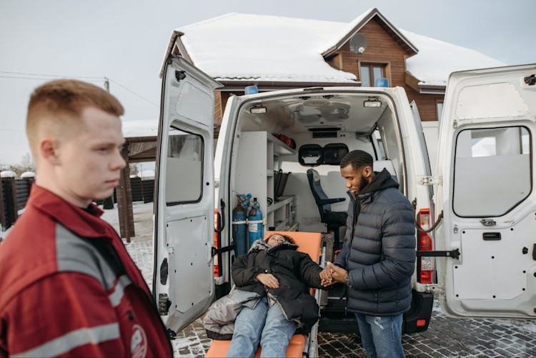Man holding Woman's hand by Ambulance before she gets taken and transported to a medical facility
