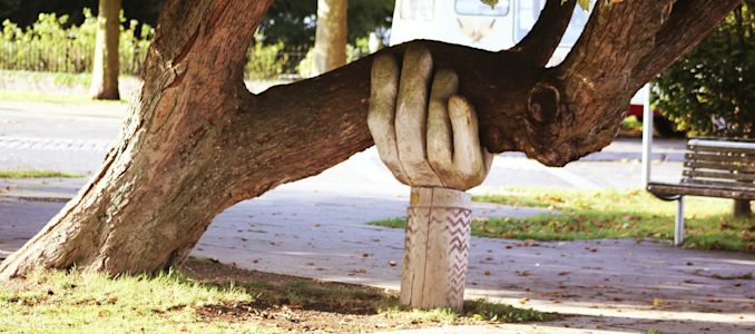 Main sculptée soutenant une grosse branche d'arbre