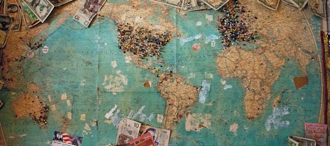 Carte du monde avec des épingles épinglées dessus et des billets de banque