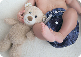 A baby in a cloth diaper with a toy
