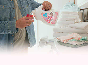 Liquid detergent is poured into the washing machine to get poop stain out of baby clothes