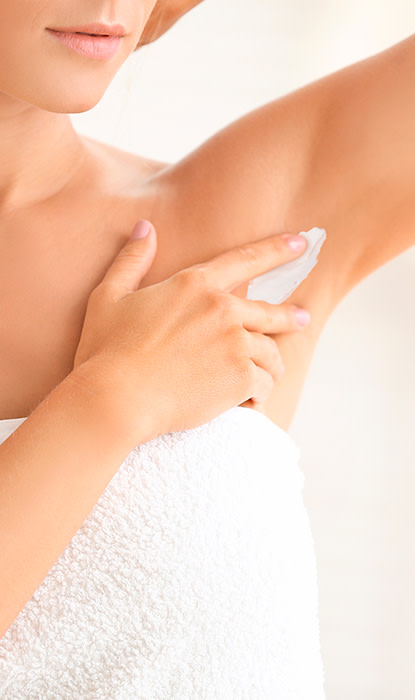 Donna che indossa un asciugamano e si applica la crema sull'avambraccio