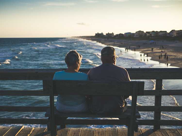elderly couple sitting at a beach