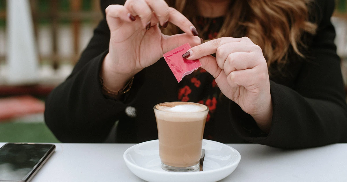 Woman adding artificial sweetener to her coffee