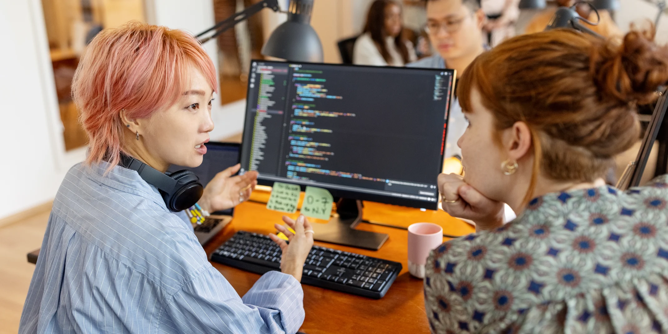 Two women sit at a computer talking