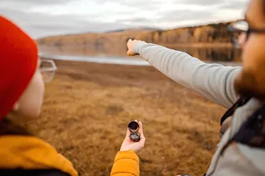 Hikers using a compass and pointing in the distance