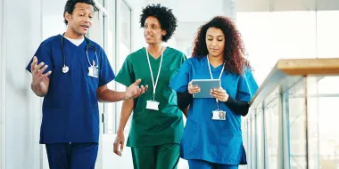 Three nurses walking and one is on a tablet