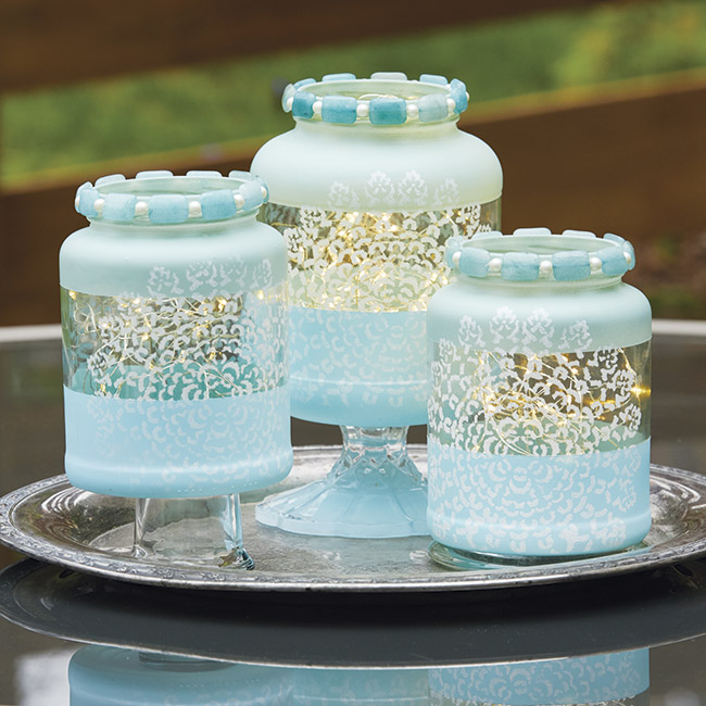 diy-jar-lantern-add-height: An assortment of candle holders used as a base elevate the lanterns in this grouping.