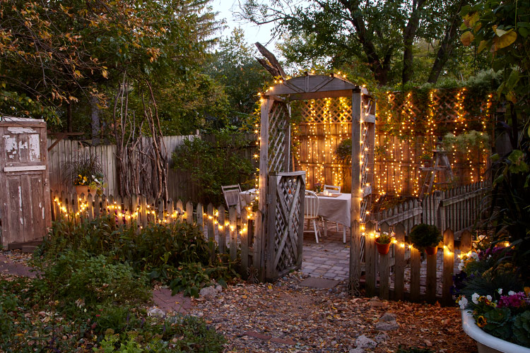 Add string lights to your garden for a warm glow:  Hang string lights on a fence with clips or tiny hooks. A timer makes turning on the lights hassle free — especially if your outlets are in difficult-to-reach places. 