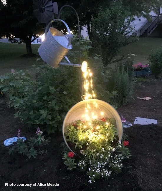 Watering can with string lights yard art