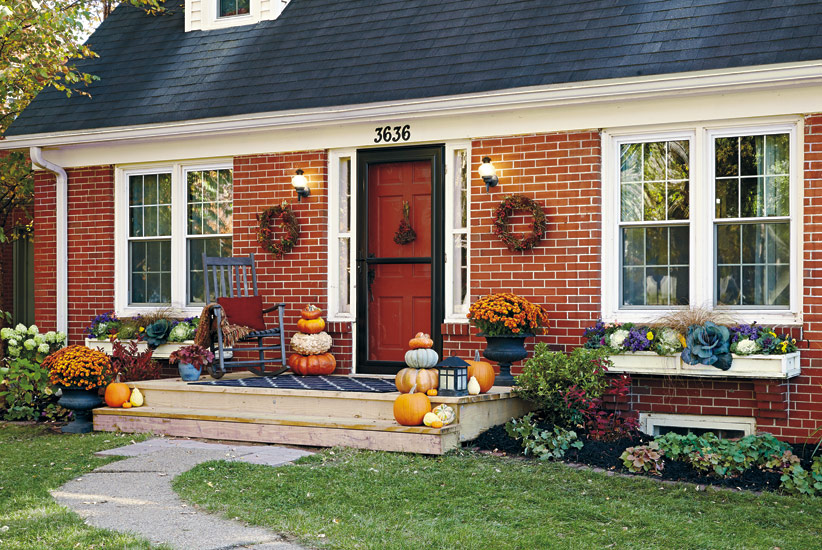 Fall curb appeal with fall flowers and pumpkins: This entry has the whole package - plenty of color on the porch and windowboxes on either side too.