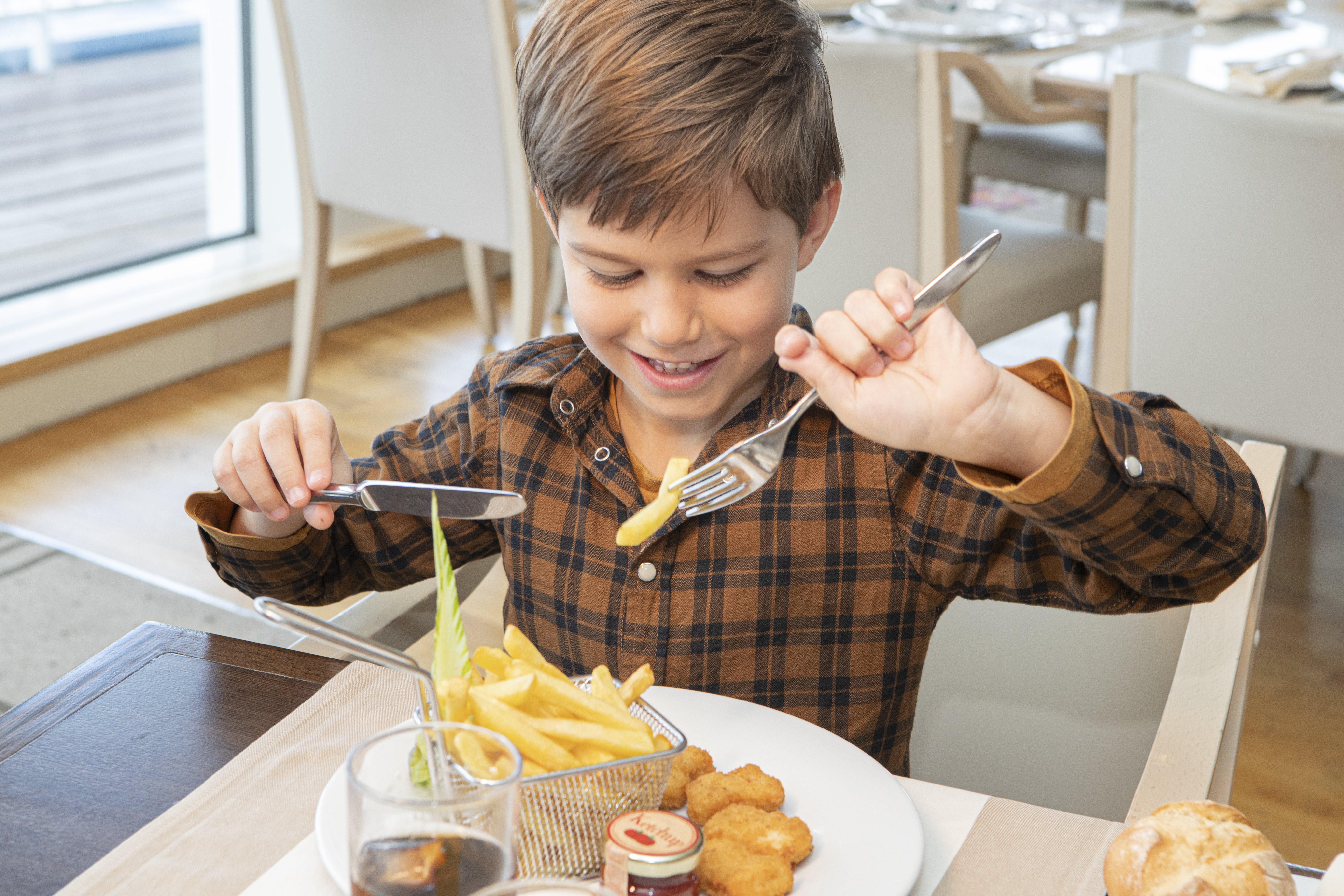 Boy eating chips in restaurant on Pont-Aven