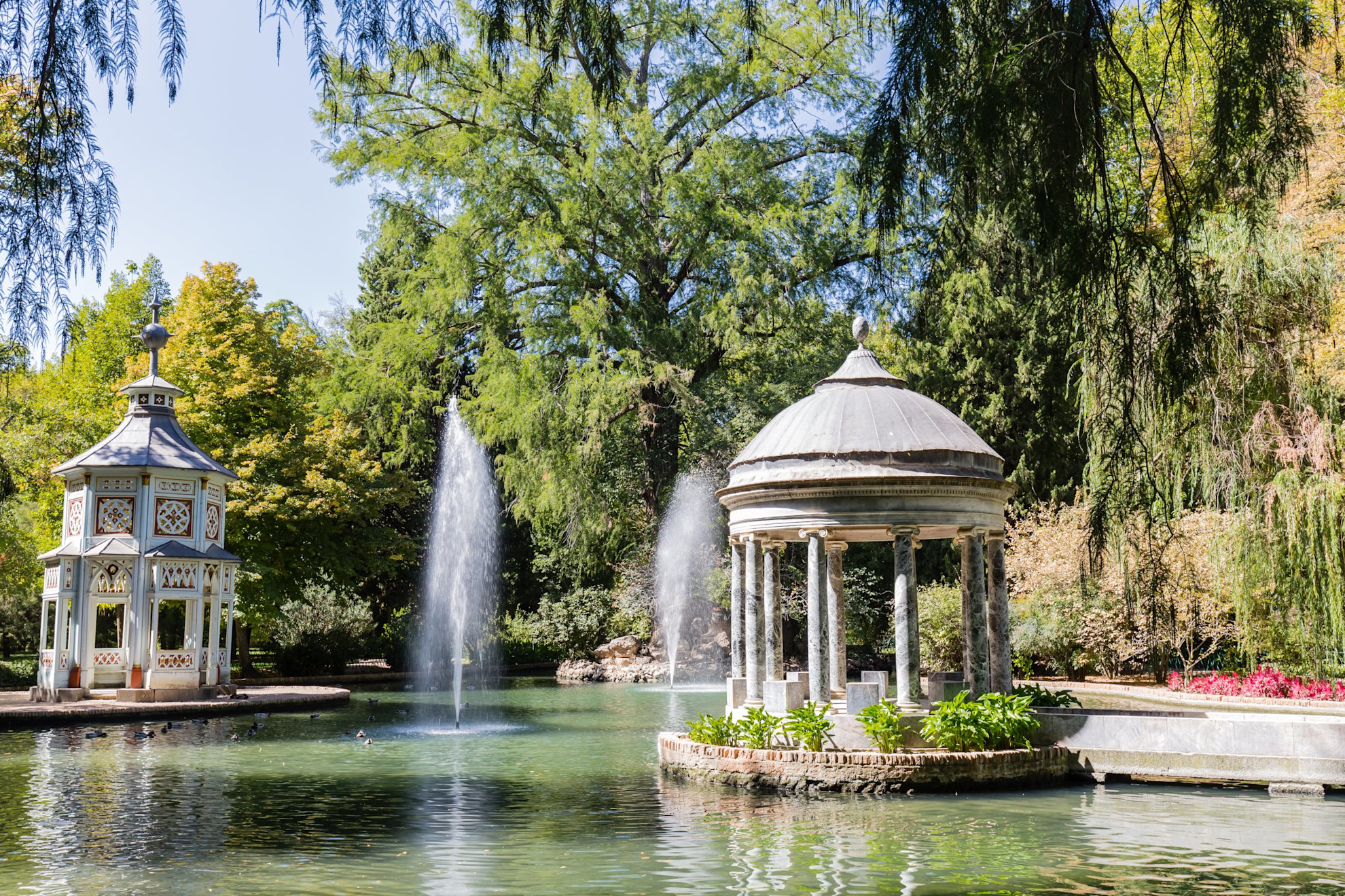 View of a pond with water features, fountains and greenery surrounding