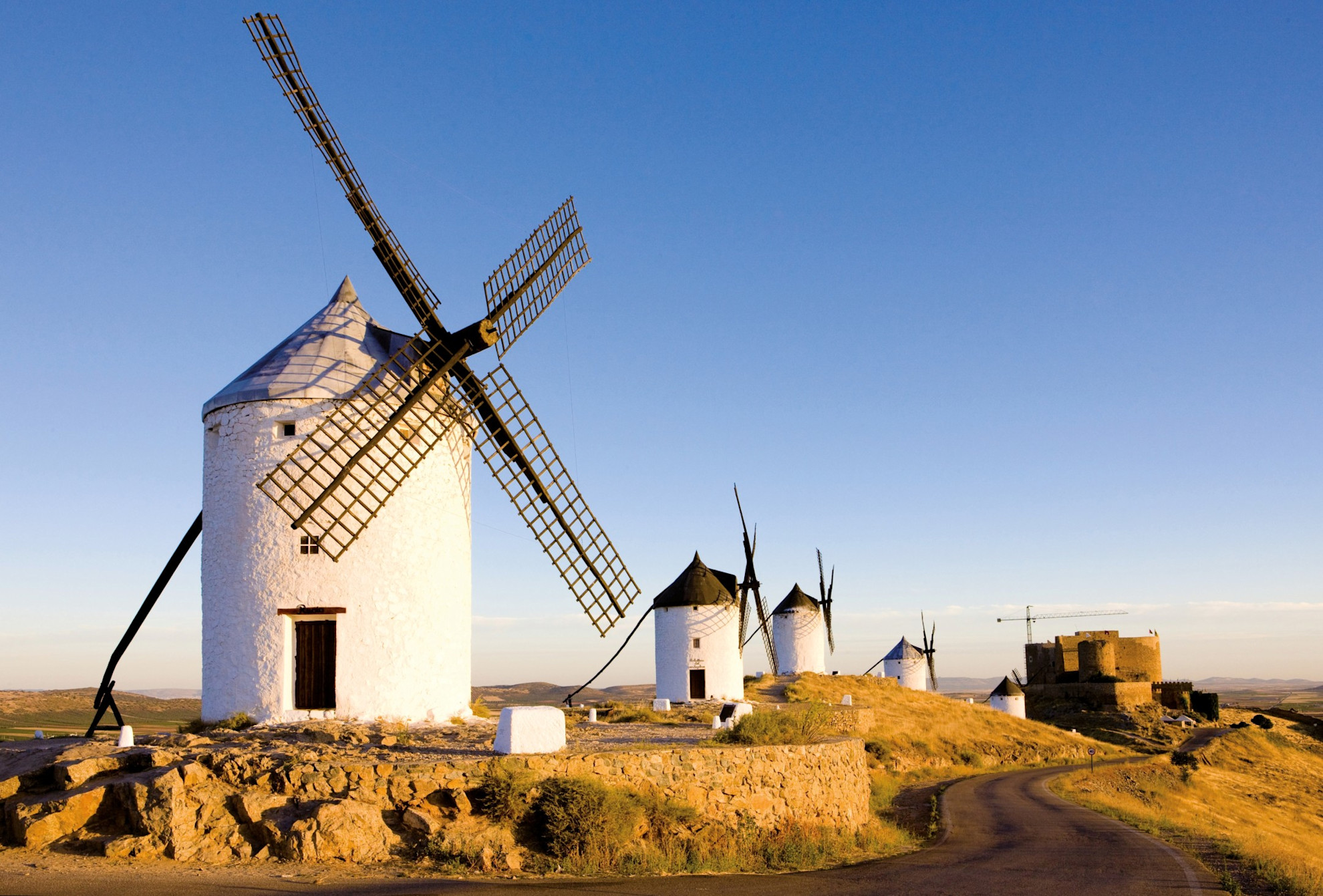 Windmills on a hillside with a castle in background. Consuegra, Castilla La Mancha