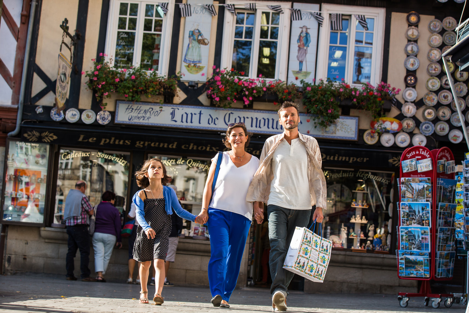 Family walking along a street in Quimper through a street with gift shops