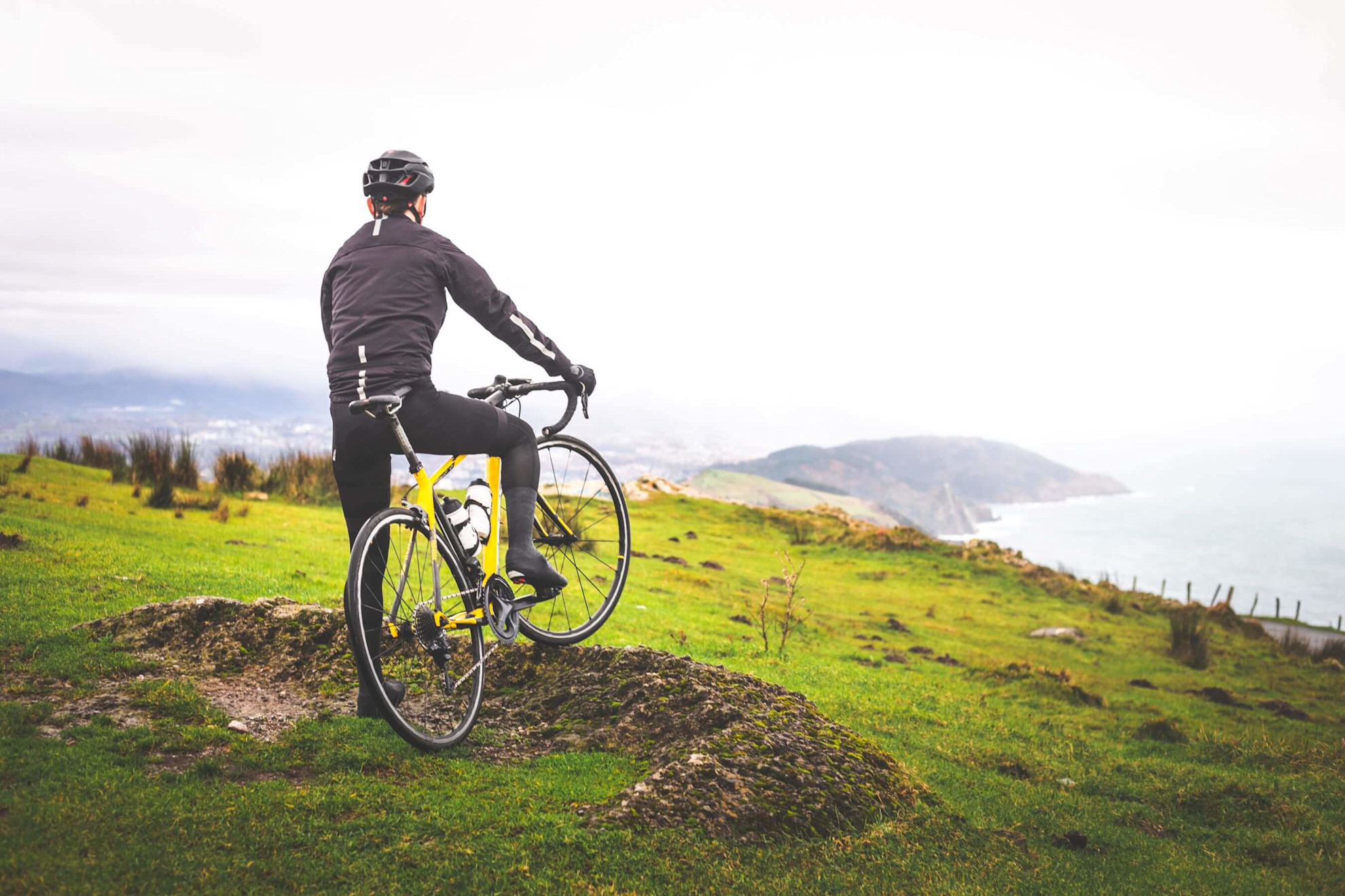 Cyclist on the top of Jaizkibel mountain with views to the Basque Country, Spain