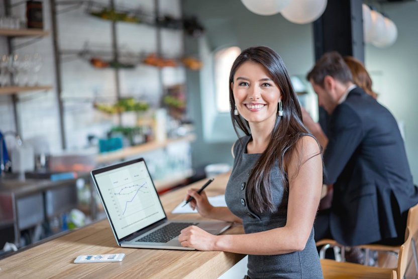 Woman smiling with graphs on a computer