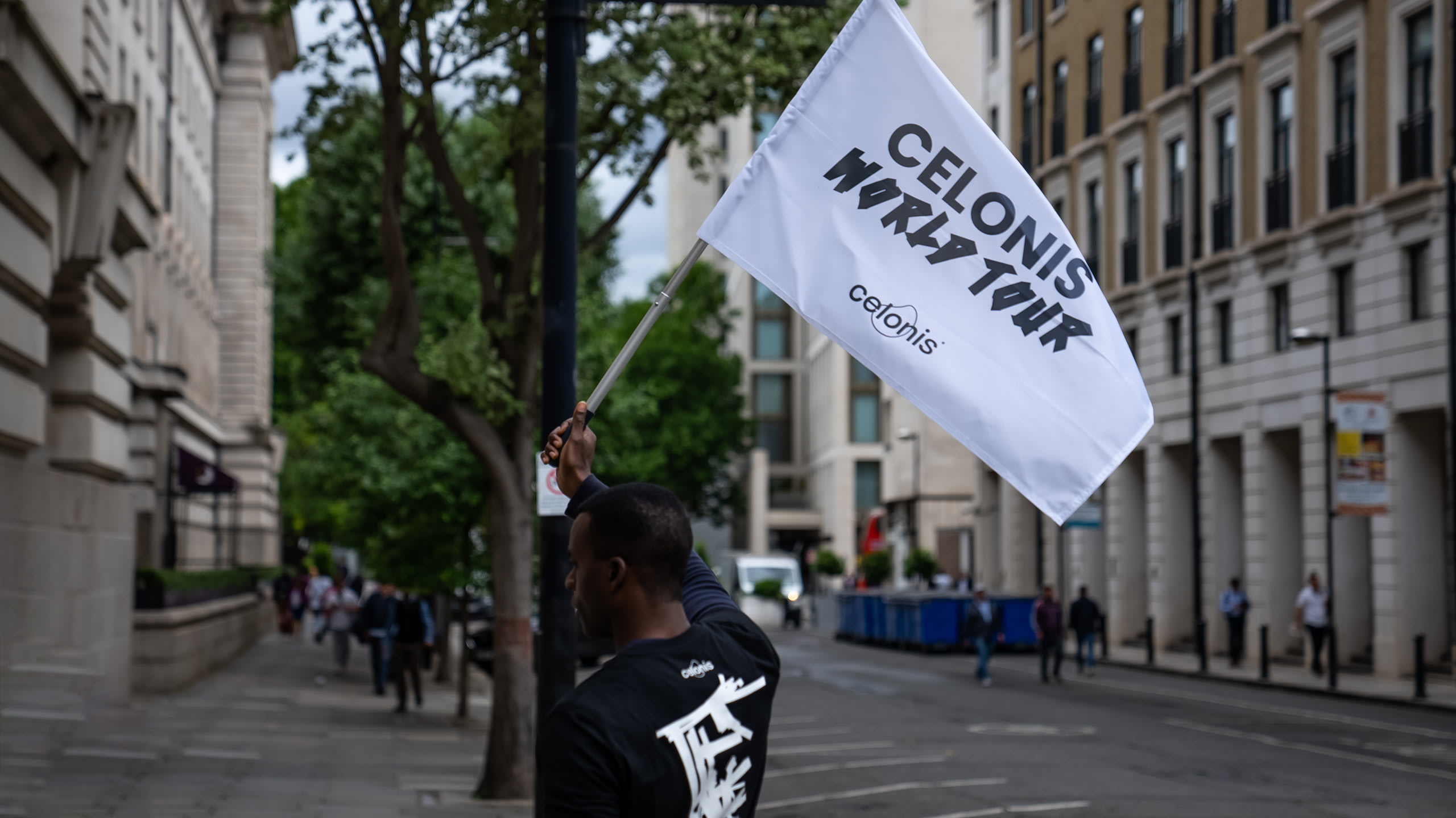 Man holding Celonis World Tour white flag on street outside London event