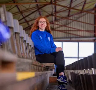 A young woman sits on a seat within the stand at Palmerston Park.