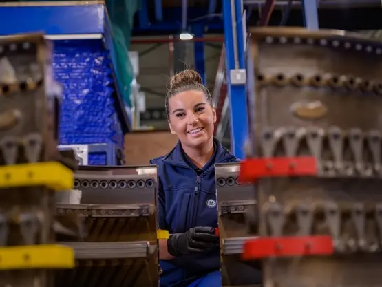 A young woman smiles while sitting between two aircraft parts.