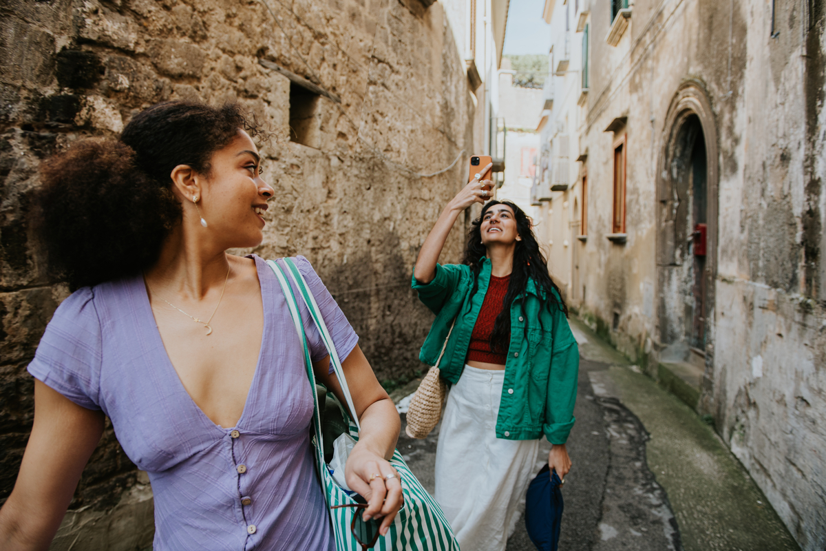A person walking through an alley, looking back at their friend taking a photo.