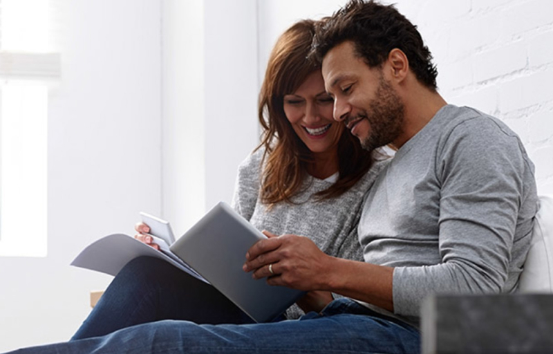 A couple (man and woman) sitting down looking at a booklet