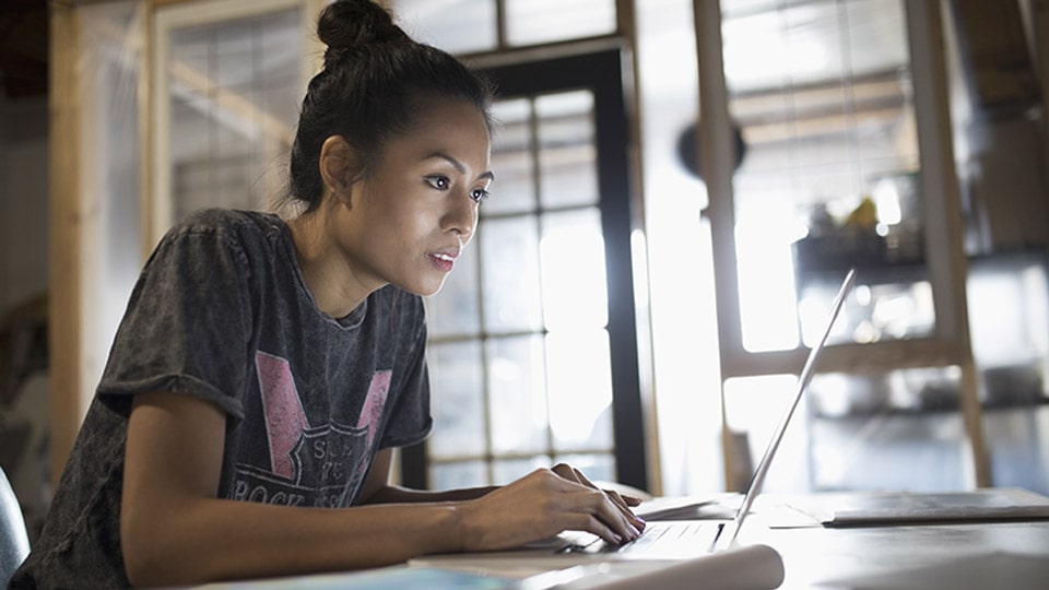 A young woman types on her laptop